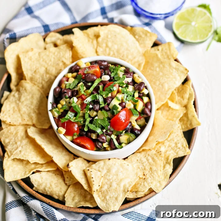 overhead photo of a white bowl of zucchini salsa with tortilla chips surrounding it