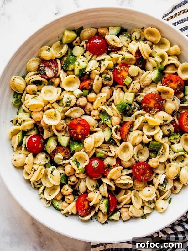 Mediterranean Chickpea Pasta Salad with cherry tomatoes and chopped cucumber in a large serving bowl.