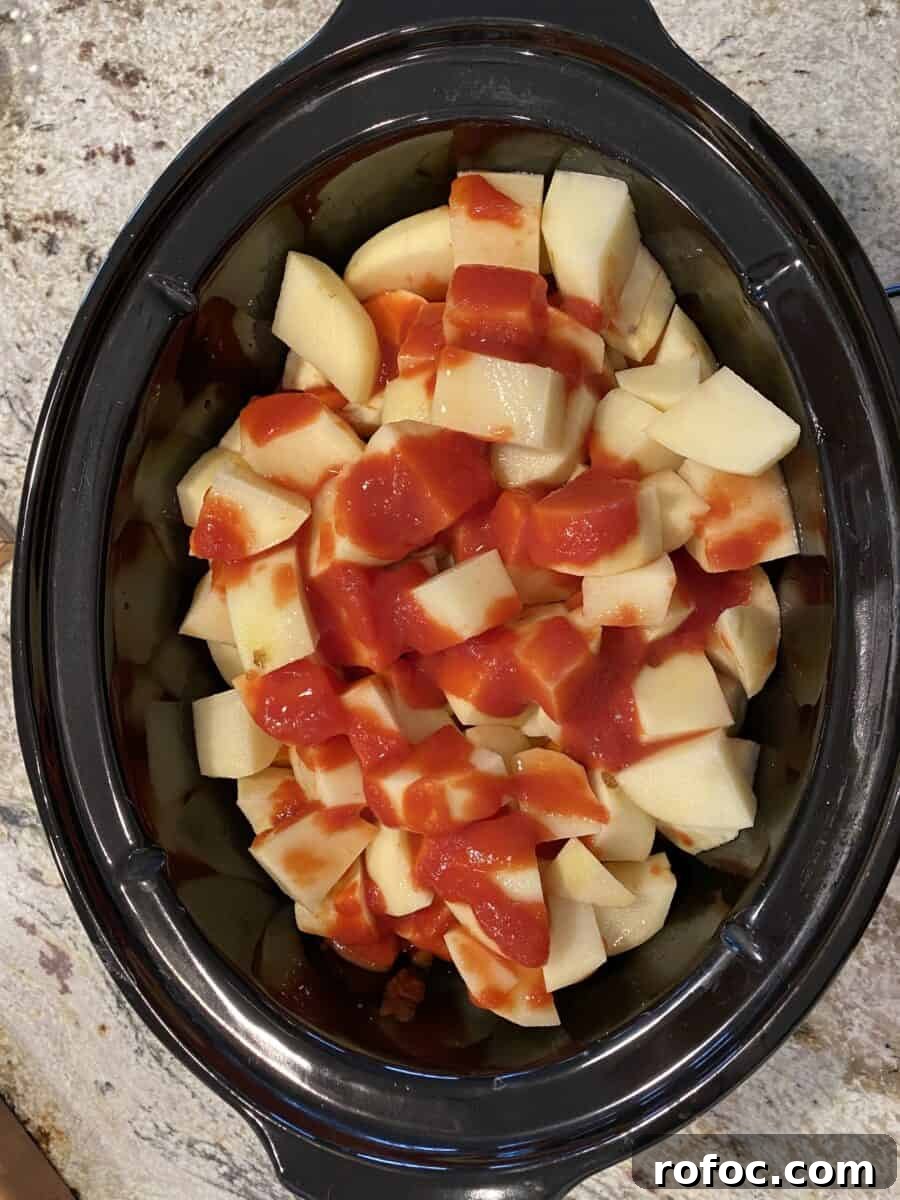 Traditional Irish Beef Stew Recipe for Hearty Weeknight Dinners 12 Tomato sauce on top of veggies and beef in a crockpot.