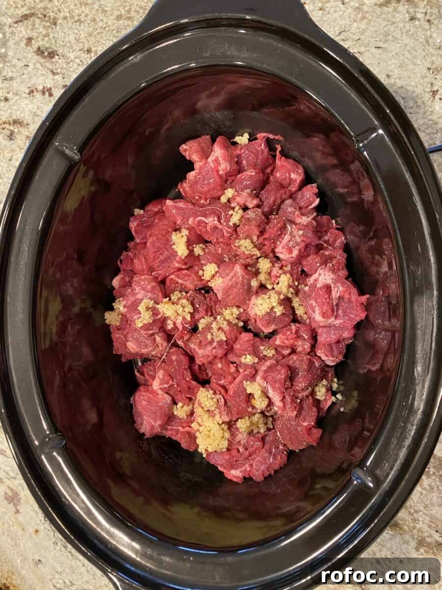 Traditional Irish Beef Stew Recipe for Hearty Weeknight Dinners 9 Beef and garlic in a crockpot.