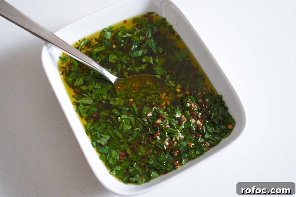 Grilled Pork Tenderloin with Fresh Chimichurri Sauce 3 Chimichurri sauce in a white rectangular bowl with a spoon in it.