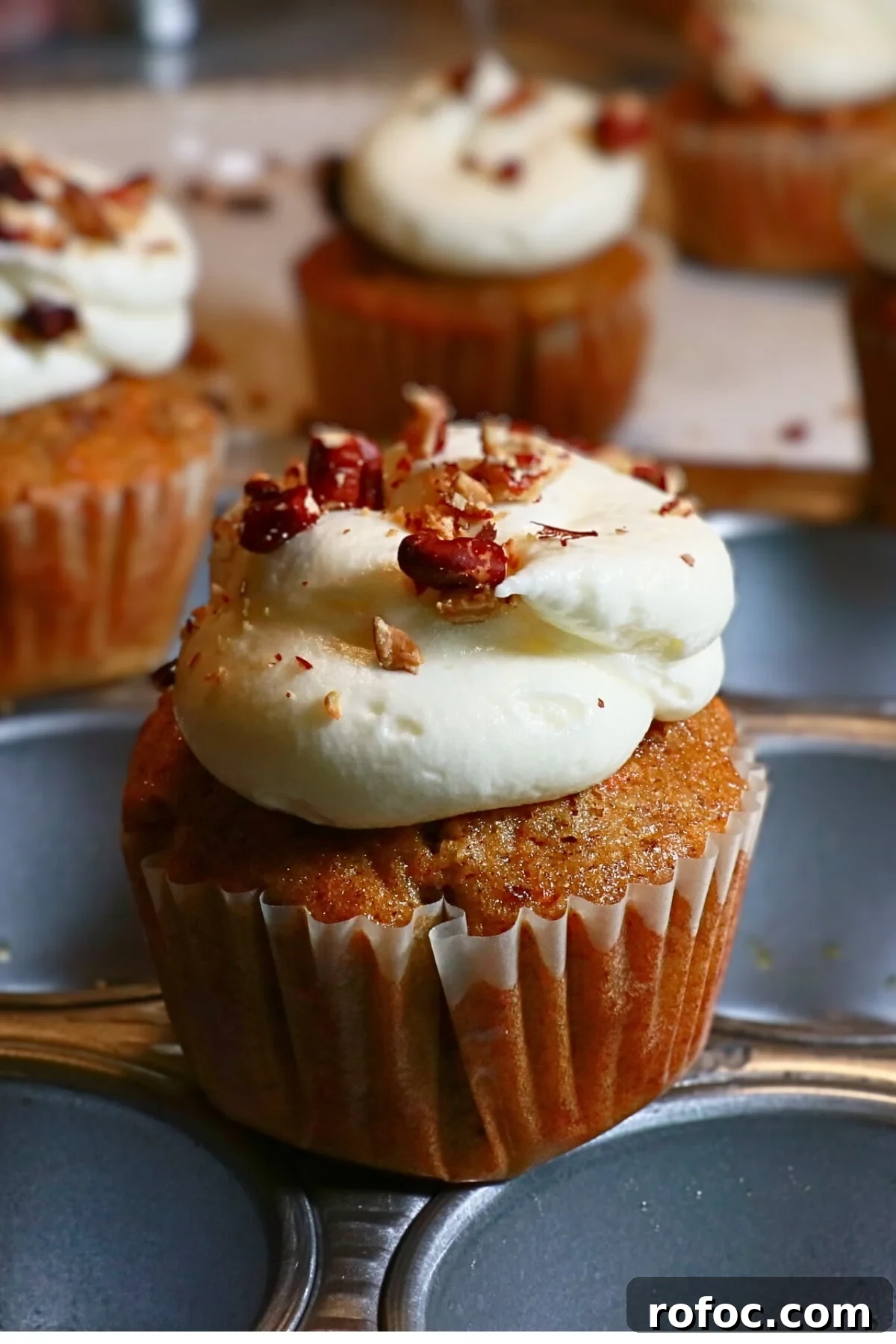 Moist Carrot Cake Cupcakes with Cream Cheese Frosting 2 homemade carrot cake cupcakes frosted with cream cheese frosting on top on a cupcake pan