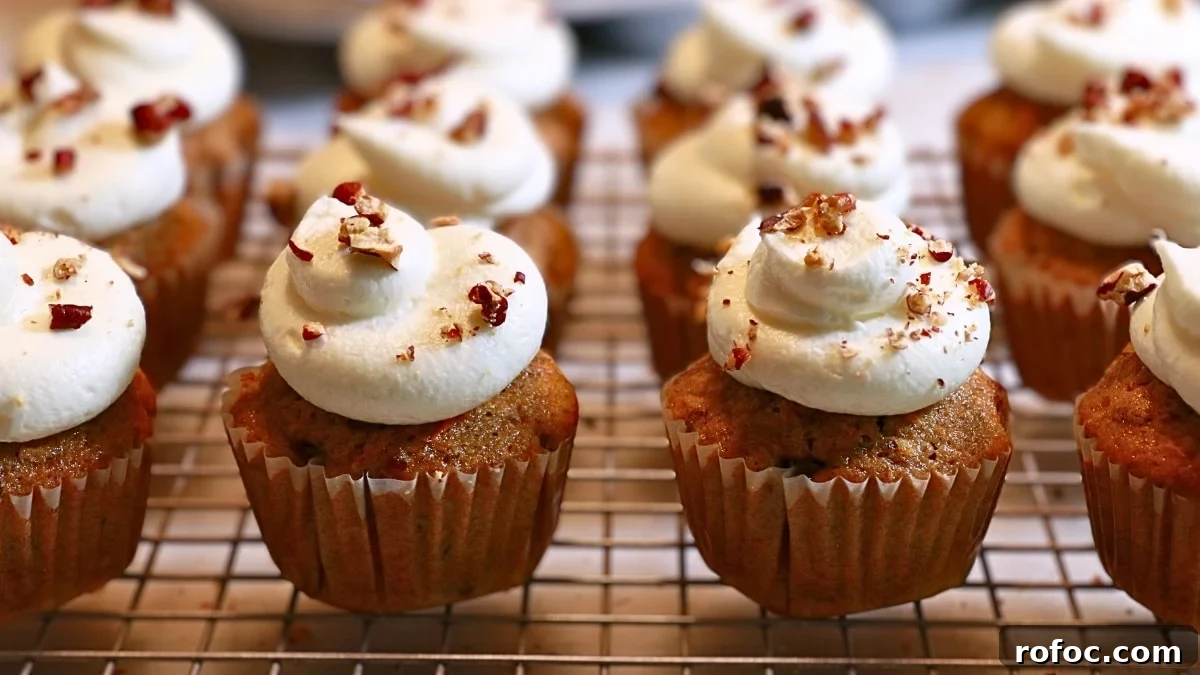 Moist Carrot Cake Cupcakes with Cream Cheese Frosting 12 carrot cake cupcakes frosted with fluffy cream cheese frosting on a cooling rack