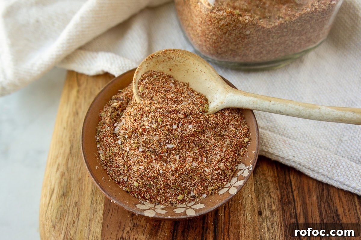 a bowl of taco seasoning on a wooden cutting board with a white spoon inside it.