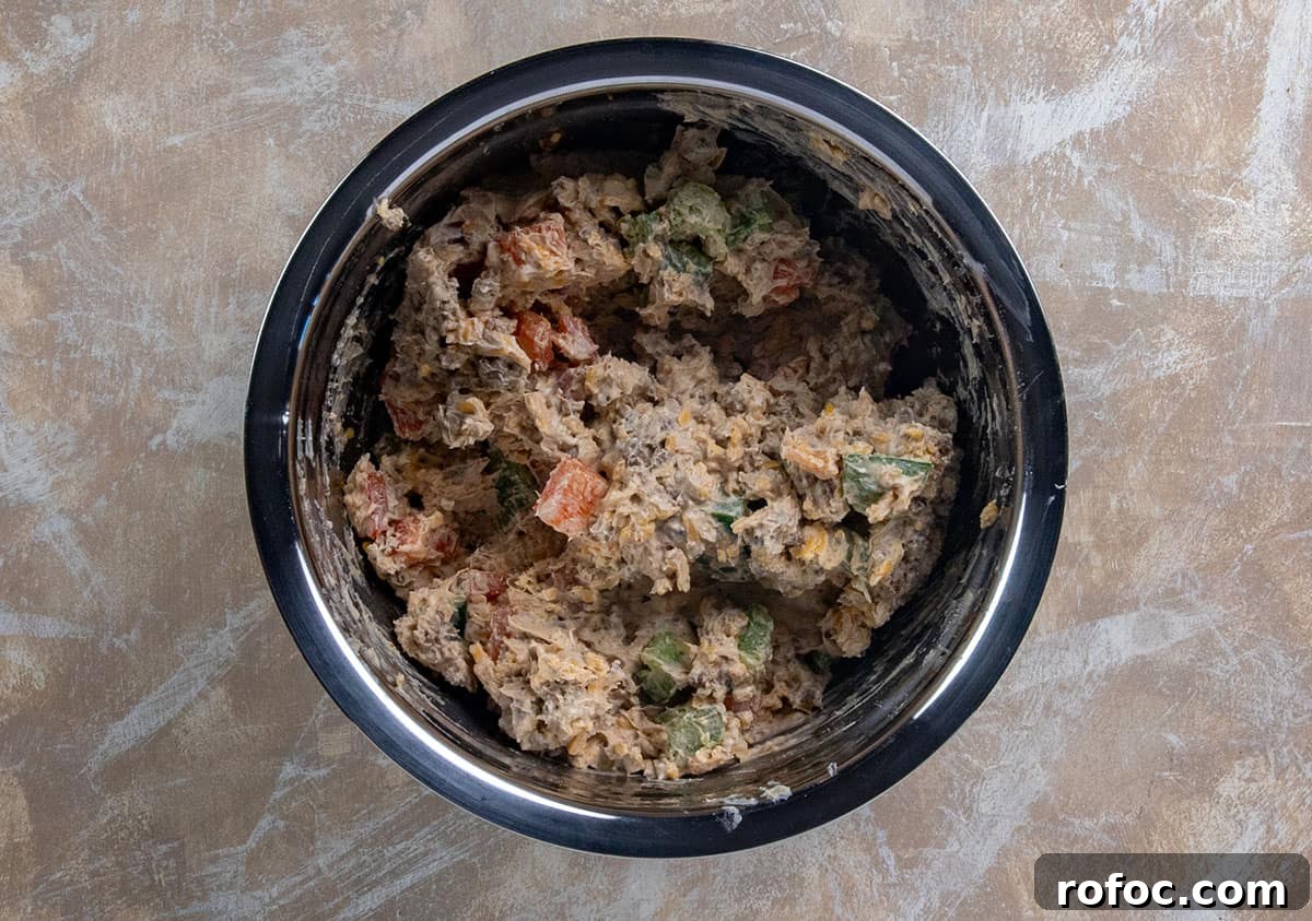 Taco Meat Pinwheels: Quick Party Appetizers from Leftovers 4 Taco meat, cream cheese, shredded cheese, red and green bell peppers mixed up in a stainless steel bowl.