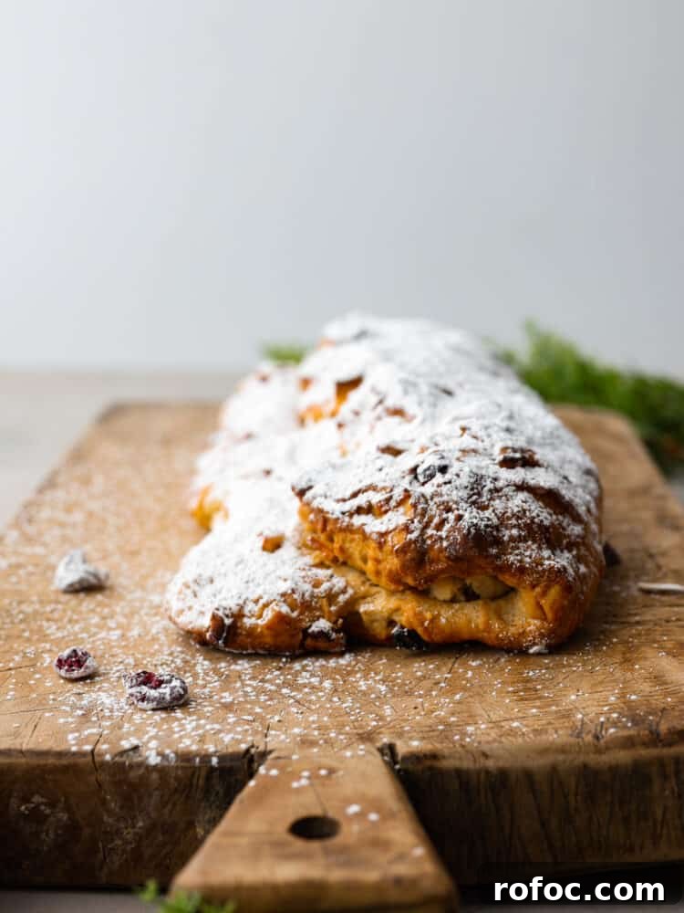 A finished loaf of stollen ready to serve. A loaf of stollen on a wooden board.
