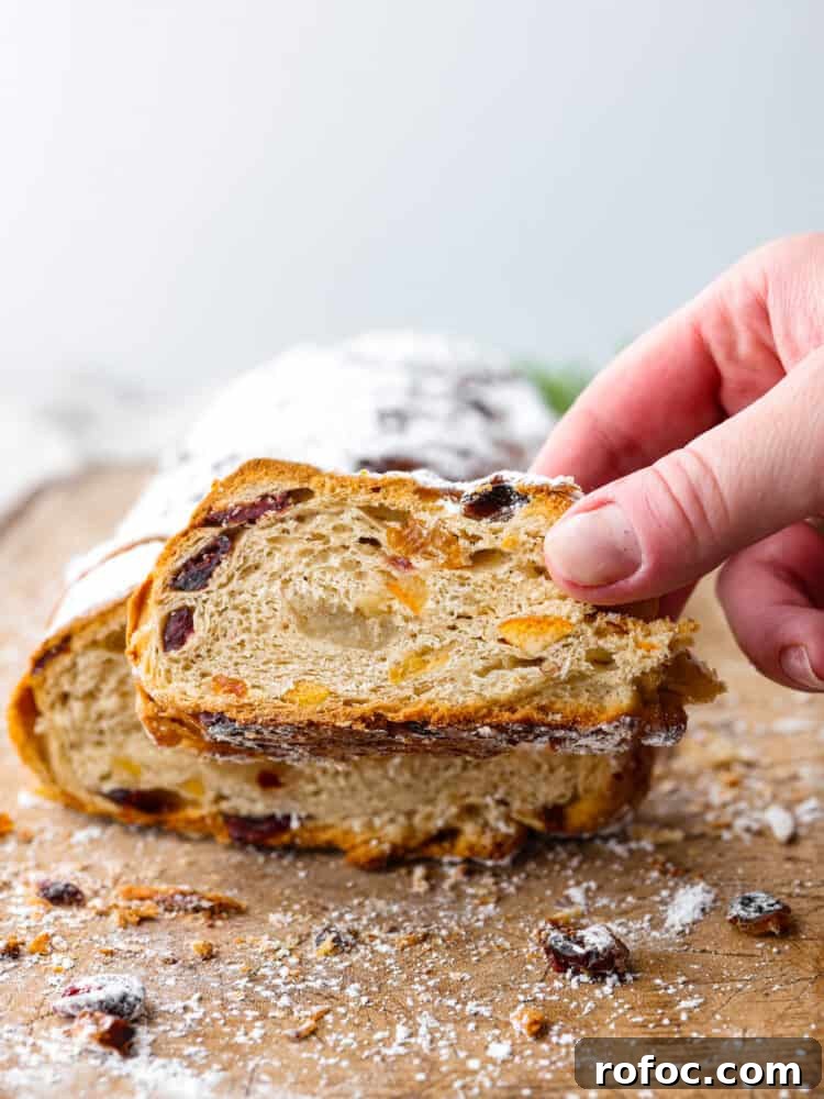 Slice of stollen being served. Front view of stollen with a slice being picked up.