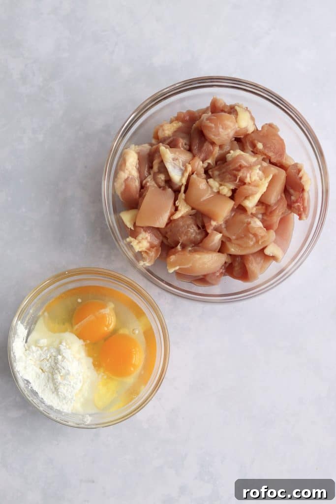 Crispy Sesame Chicken Recipe with Sticky Sweet Sauce 3 Raw chicken thighs in a bowl and eggs and cornstarch in a bowl