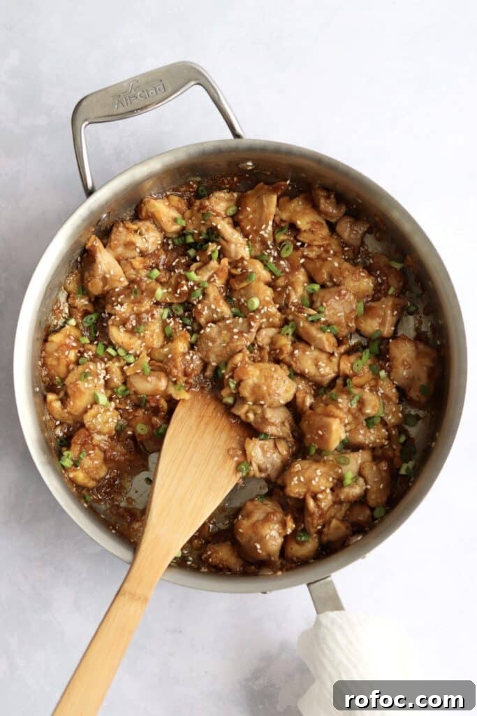 Crispy Sesame Chicken Recipe with Sticky Sweet Sauce 4 Sticky, sesame chicken in a pan with green onions and sesame seeds