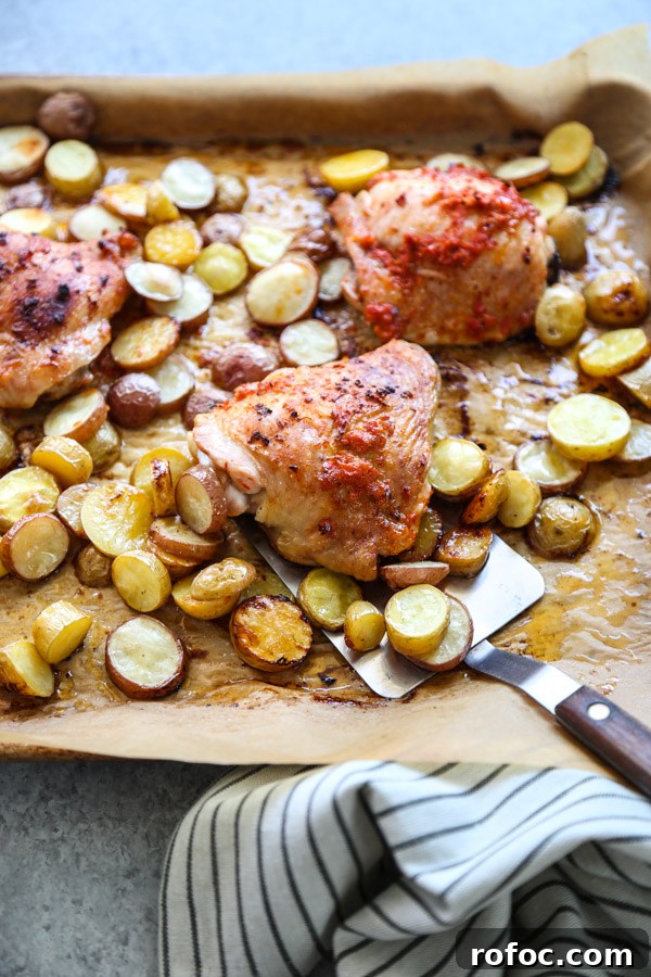 Portuguese Piri-Piri Chicken Thighs with Roasted Potatoes 8 spatula holding partuguese peri peri chicken and potatoes on a sheet pan