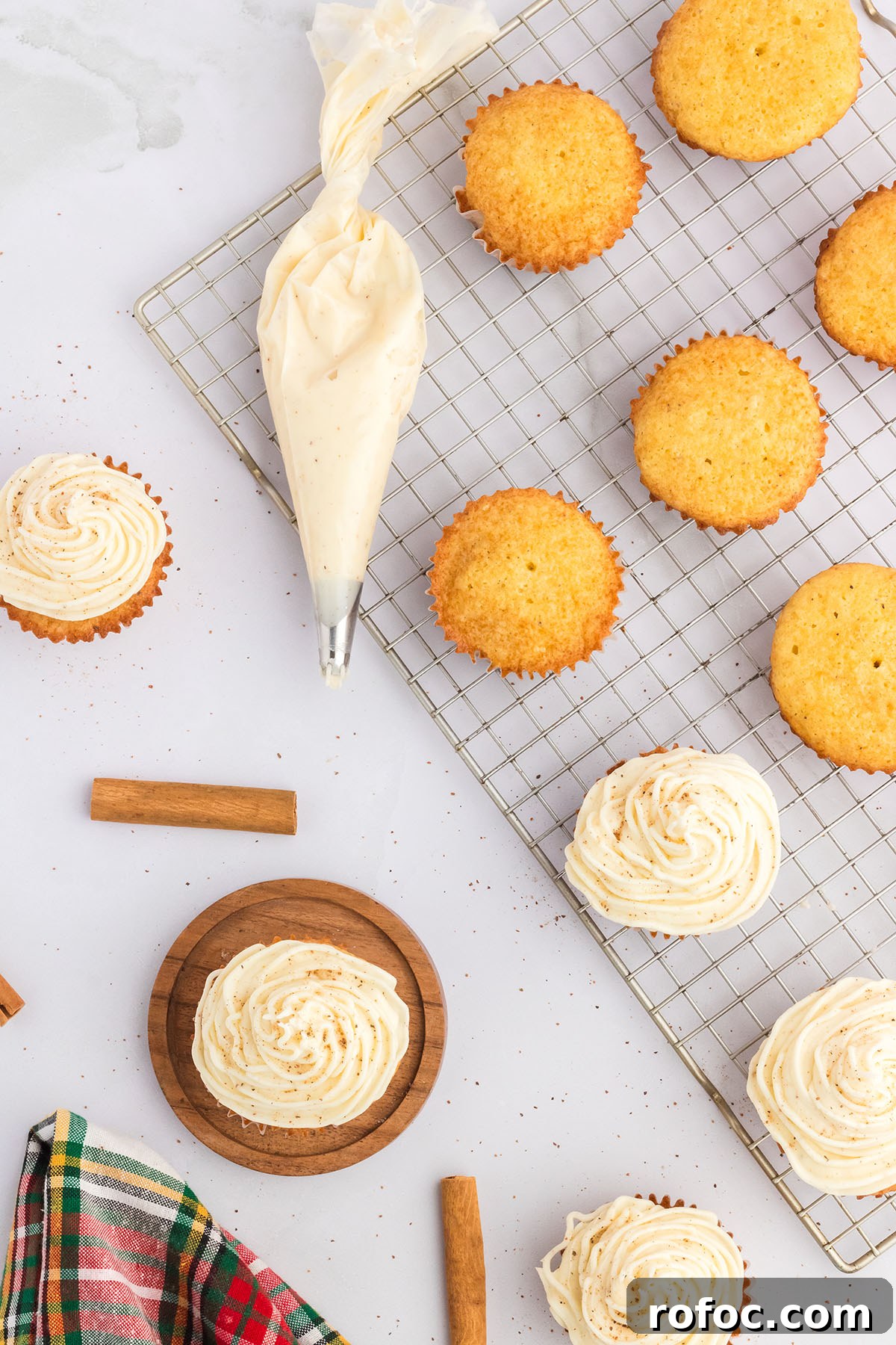 Eggnog Cupcakes with Spiced Rum Buttercream Filling 11 Frosting eggnog cupcakes on a wire rack.