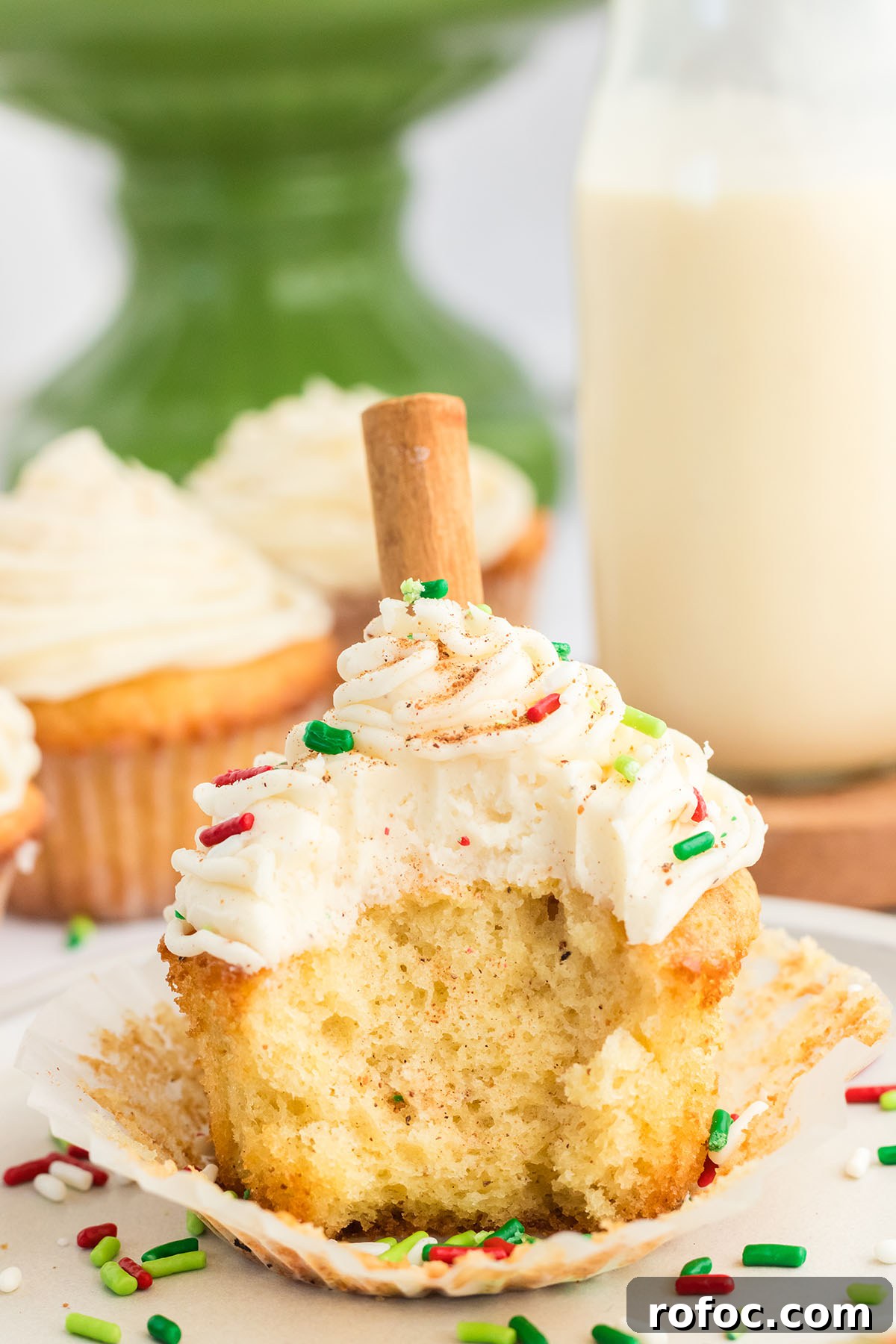 Eggnog Cupcakes with Spiced Rum Buttercream Filling 13 Eggnog cupcake topped with sprinkles with a bite taken out of it.