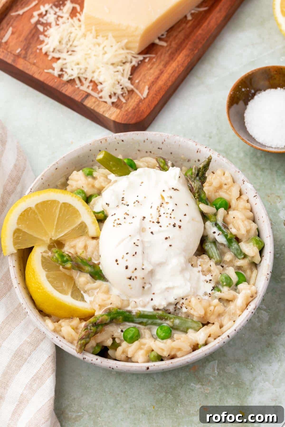 Creamy Asparagus and Pea Risotto with Burrata Cheese 2 A bowl of risotto with peas, asparagus, burrata and lemon wedges.