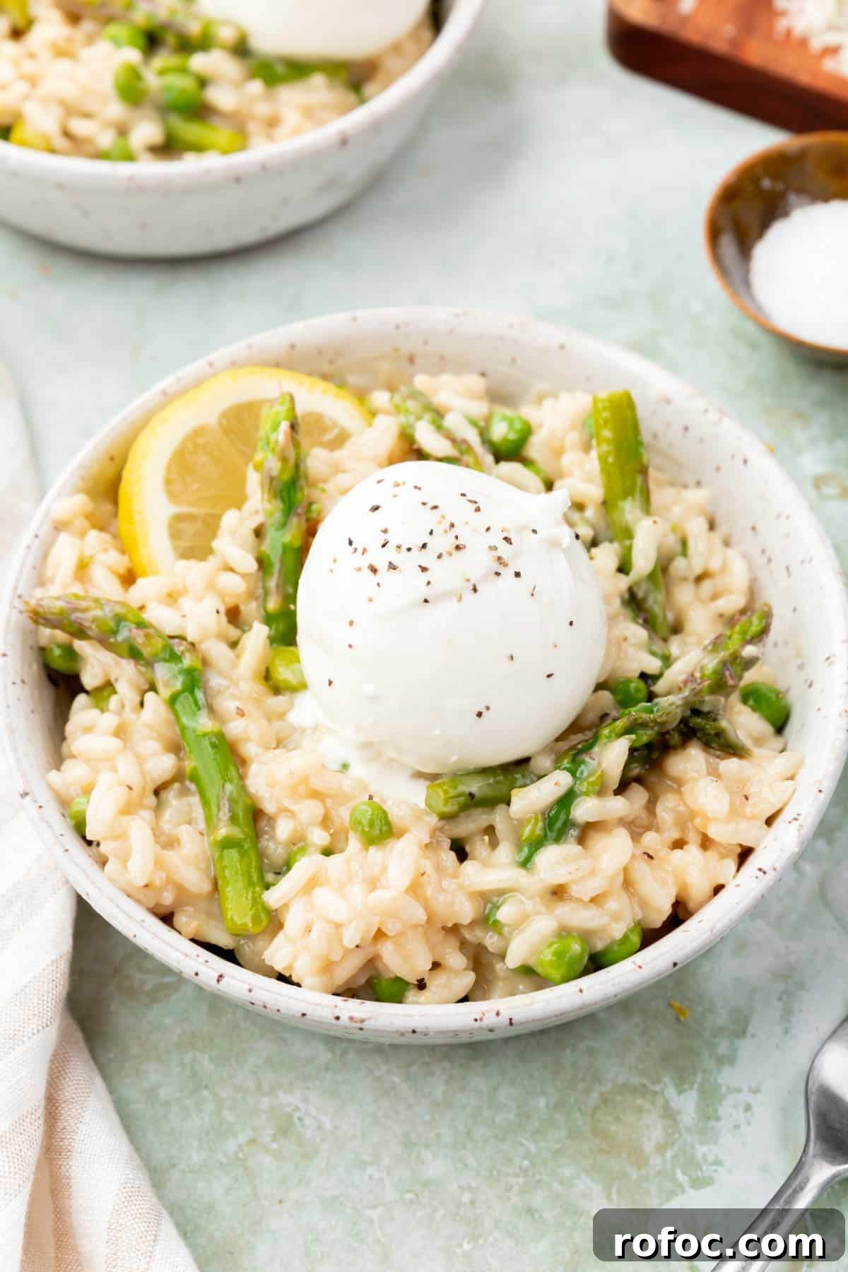 Creamy Asparagus and Pea Risotto with Burrata Cheese 11 A bowl of pea and asparagus risotto topped with burrata and a lemon wedge.
