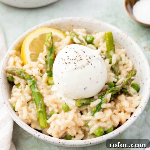 Creamy Asparagus and Pea Risotto with Burrata Cheese 13 A bowl of pea and asparagus risotto topped with burrata and a lemon wedge.