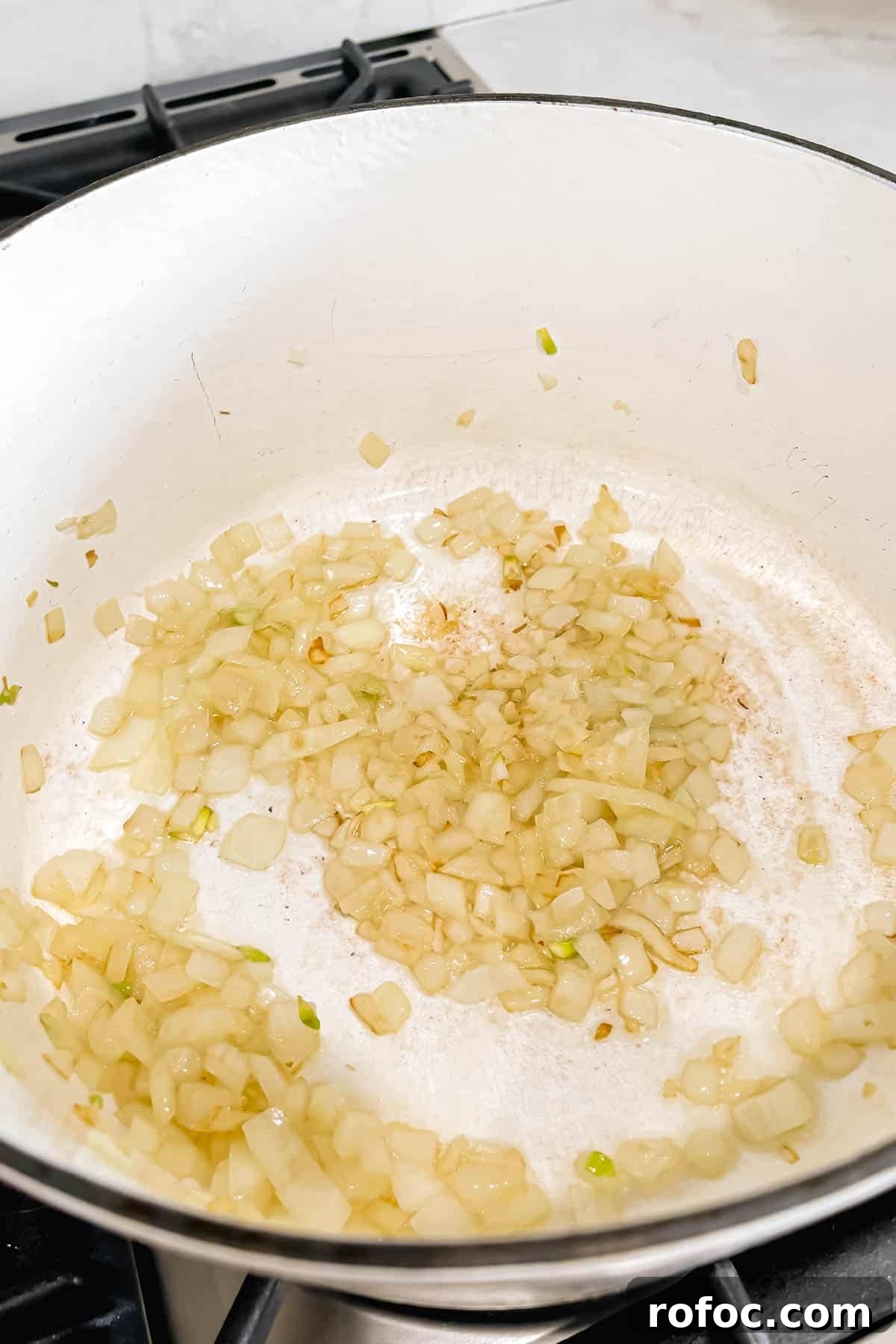 Creamy Asparagus and Pea Risotto with Burrata Cheese 5 Sautéed diced onions and minced garlic cooking in olive oil in a white dutch oven.
