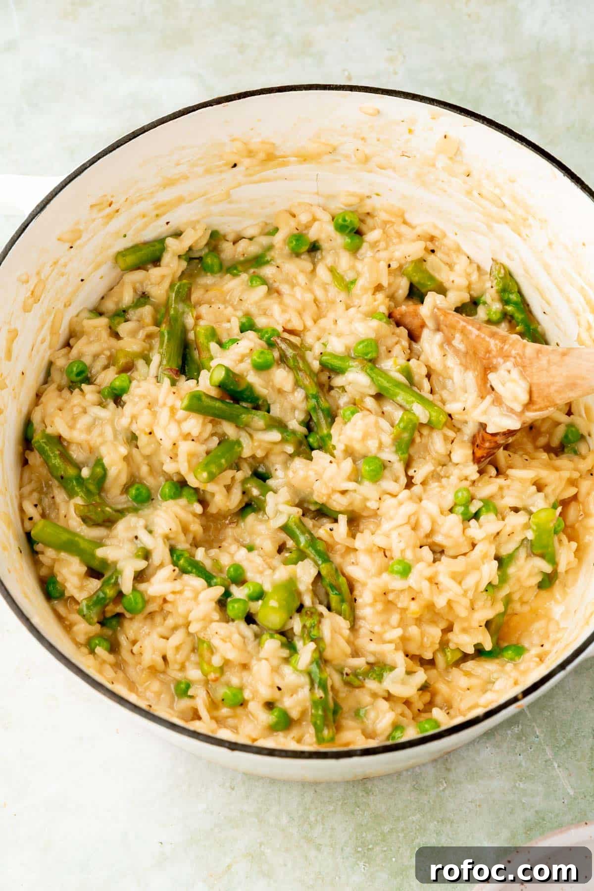 Creamy Asparagus and Pea Risotto with Burrata Cheese 10 Arborio rice mixed with asparagus and peas in a large white dutch oven.