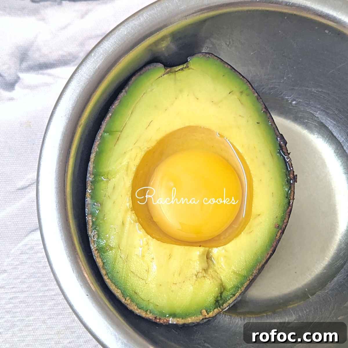 Crispy Air Fryer Avocado Eggs: Quick Breakfast Recipe 5 Half of an avocado with yolk and white in the cavity.