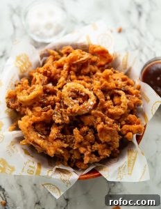 Crispy Fried Onions fried onions in wooden bowl with salt and bbq sauce blurred in background