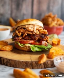 Chicken Sandwich chicken sandwich on wooden board surrounded by potato wedges and dip