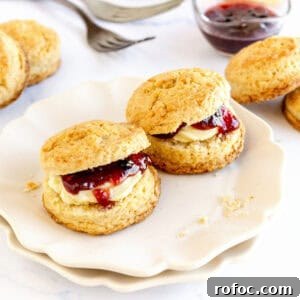 Mini Cream Scones Recipe — Simple Homemade Bite-Sized Scones 12 Jam filled scones on a white plate. White background, jam, plain scones.