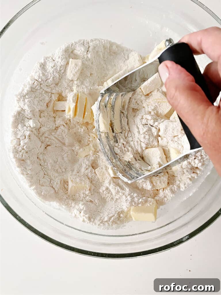Mini Cream Scones Recipe — Simple Homemade Bite-Sized Scones 6 Cutting in butter into flour mixture in a glass bowl with a pastry cutter.