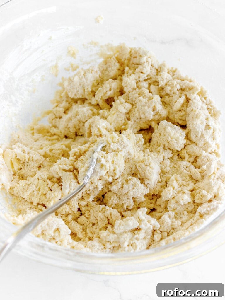 Mini Cream Scones Recipe — Simple Homemade Bite-Sized Scones 7 Silver fork in a glass bowl with shaggy scone dough.