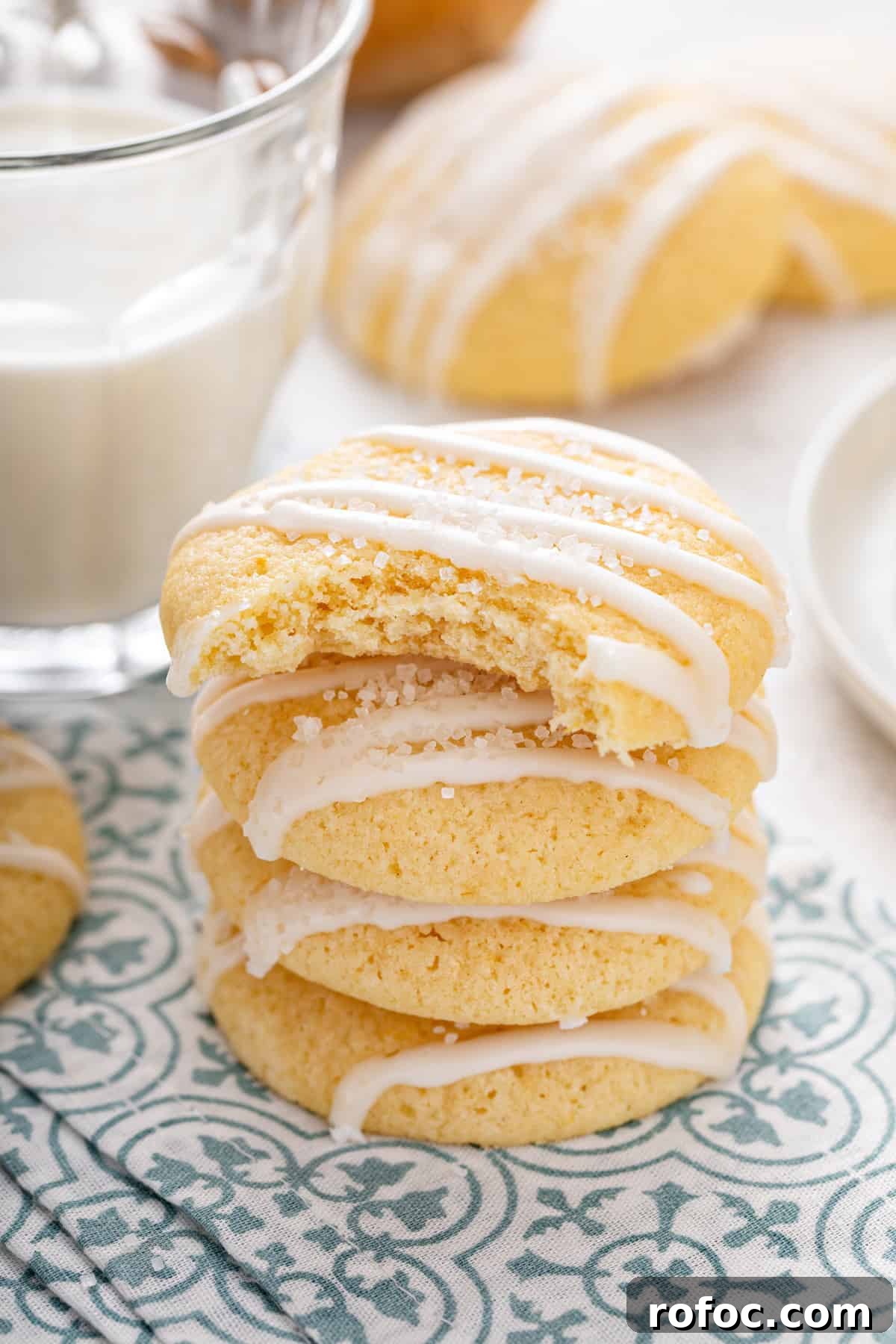 Stack of glazed pound cake cookies on a blue and white napkin. The top cookie has a bite taken from it.