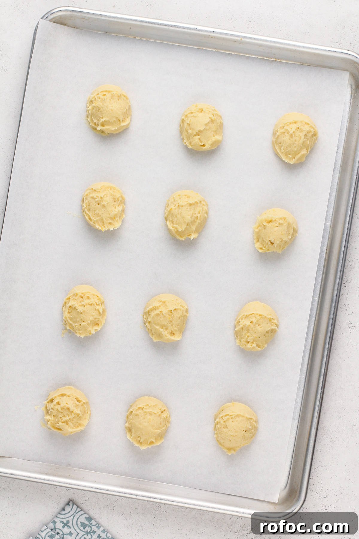 Unbaked pound cake cookies on a parchment-lined baking sheet, ready to go in the oven.