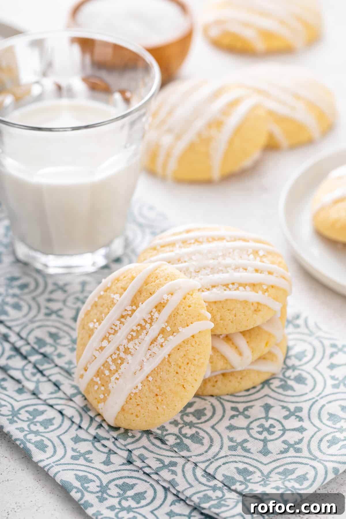 Three pound cake cookies stacked next to a glass of milk with a fourth cookie leaning against the stack.