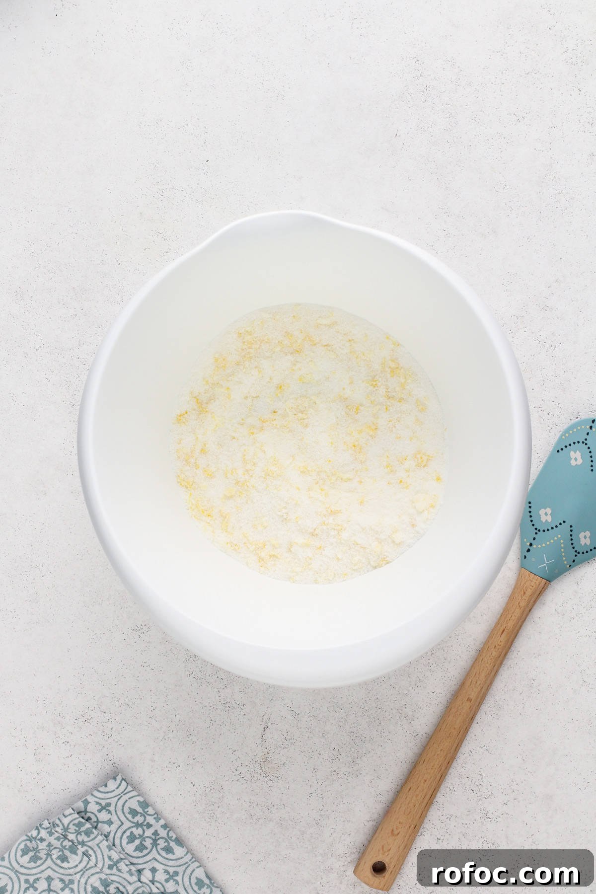 Sugar and lemon zest combined in a white mixing bowl.