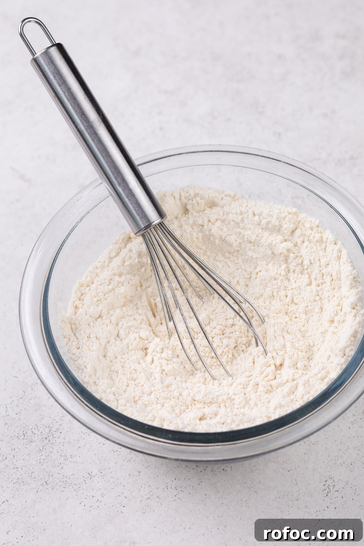 Dry ingredients for cookies whisked together in a glass bowl.