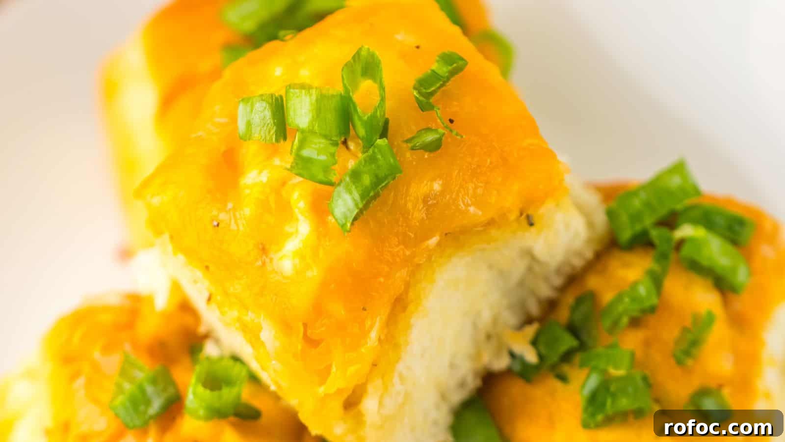 35 Gameday Recipes That Always Crowd-Pleasers Love 2 Close-up of cheesy garlic bread rolls topped with chopped green onions on a white plate, reminiscent of Loaded Buffalo Chicken Rolls.