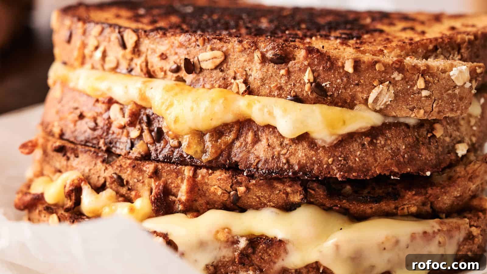 35 Gameday Recipes That Always Crowd-Pleasers Love 15 Close-up of two stacked grilled cheese sandwiches made with multigrain bread and melted cheese oozing out.