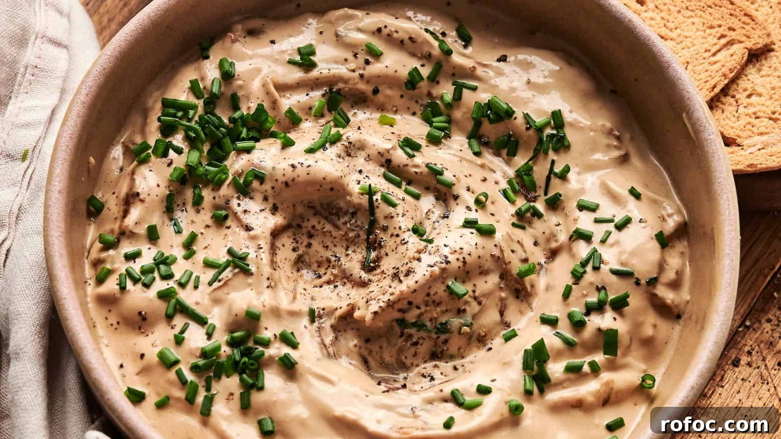 35 Gameday Recipes That Always Crowd-Pleasers Love 22 Bowl of creamy dip topped with chopped chives and black pepper, next to pieces of toasted bread.