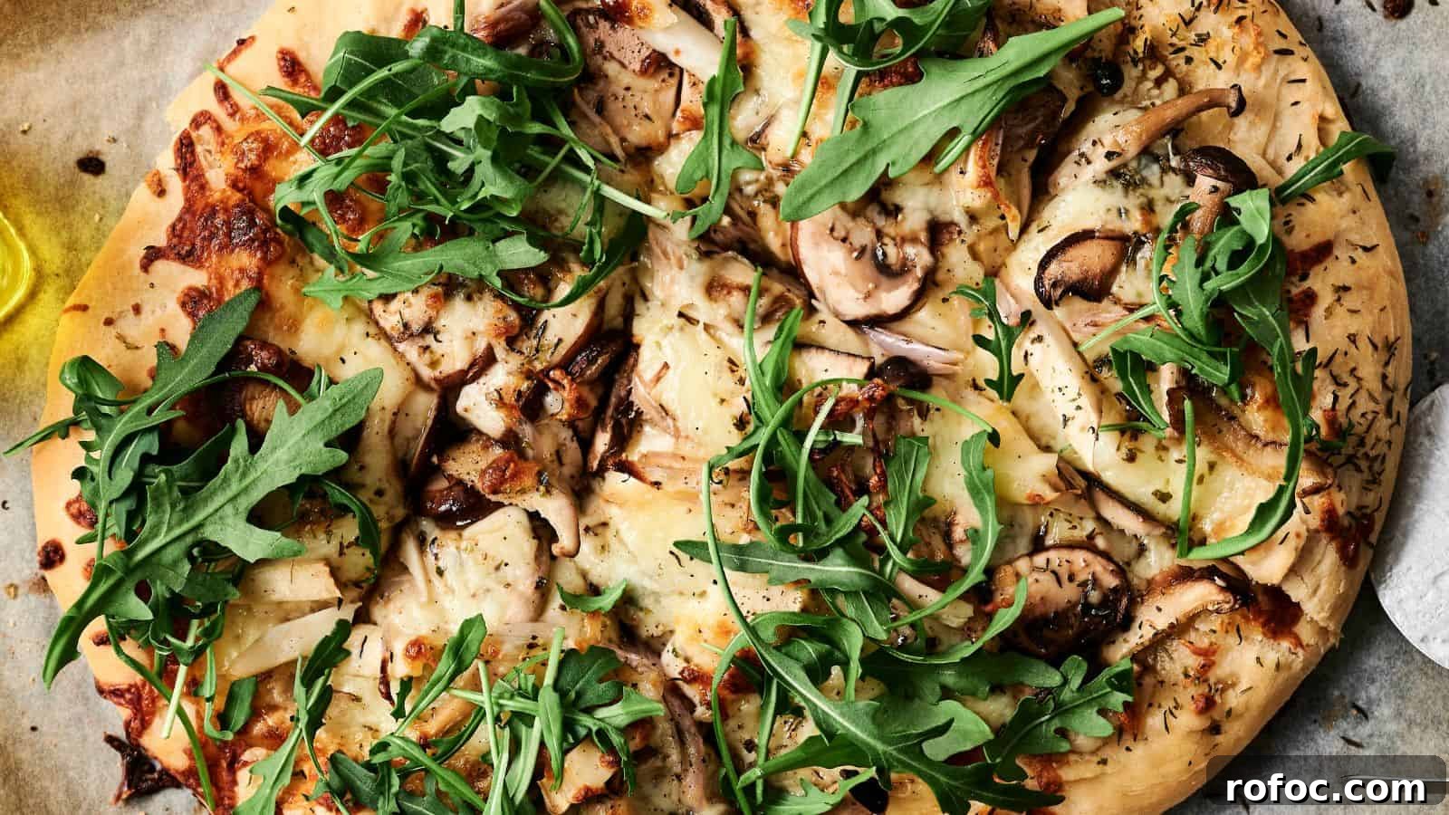 35 Gameday Recipes That Always Crowd-Pleasers Love 25 Close-up of a pizza topped with arugula, mushrooms, cheese, and herbs on a parchment paper.