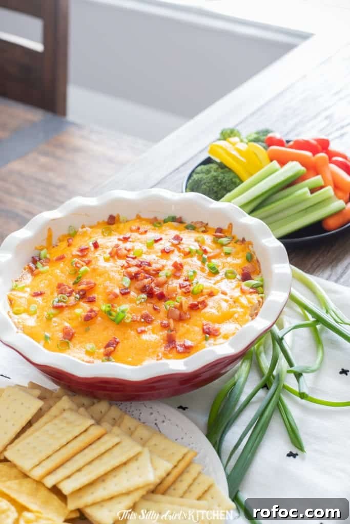 Bacon Ranch Chicken Dip in pie plate surrounded by crackers and vegetables