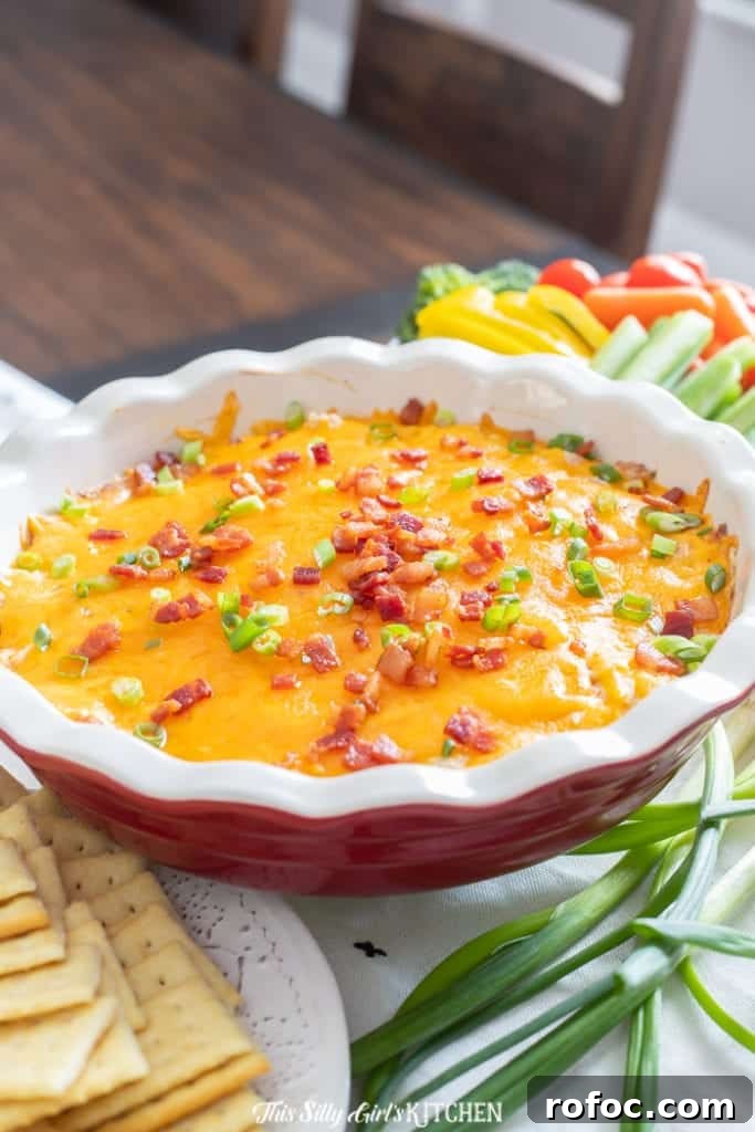 Close up of chicken dip in pie plate topped with bacon and green onions