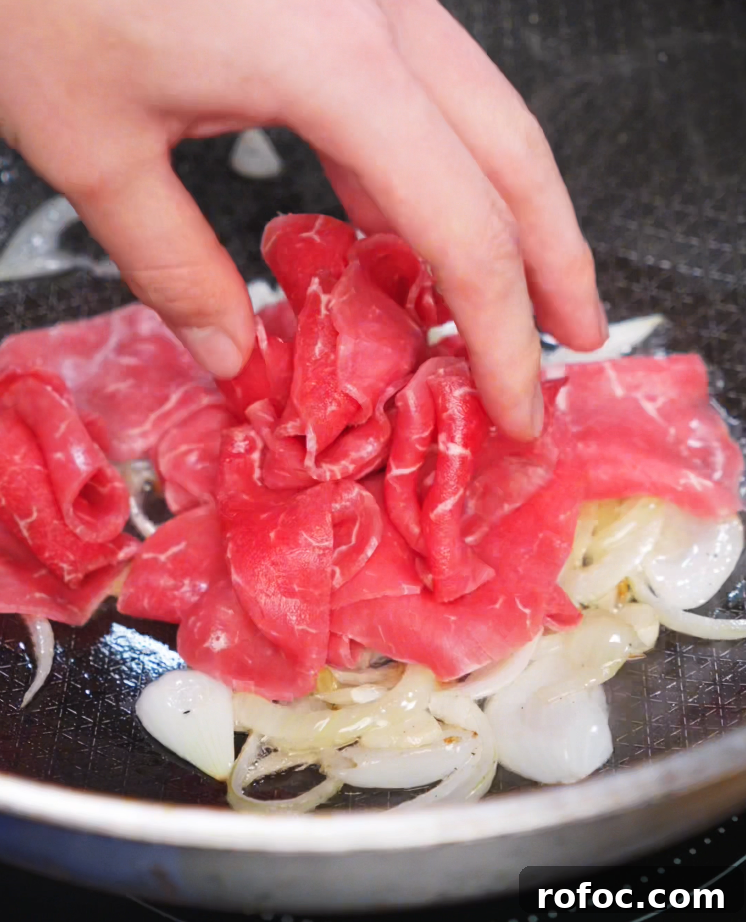 Savory Beef Curry Udon Recipe for Comforting Weeknight Meals 6 Thinly sliced beef added to onions in a hot pan.