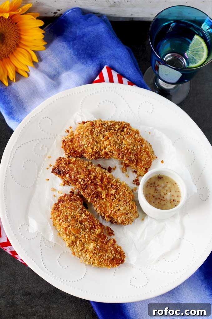 Crispy Macadamia-Crusted Chicken Tenders with Honey Lime Dip 3 Overhead shot of three Macadamia Nut Crusted Chicken Tenders and a mini white bowl with honey mustard