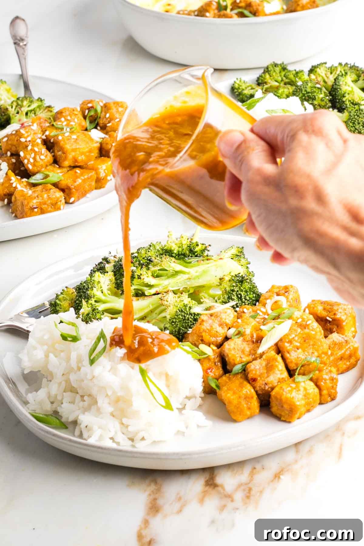 Crispy Orange Tofu — Restaurant-Style Takeout at Home 12 Extra orange sauce poured onto white rice on the dish with tofu and broccoli.