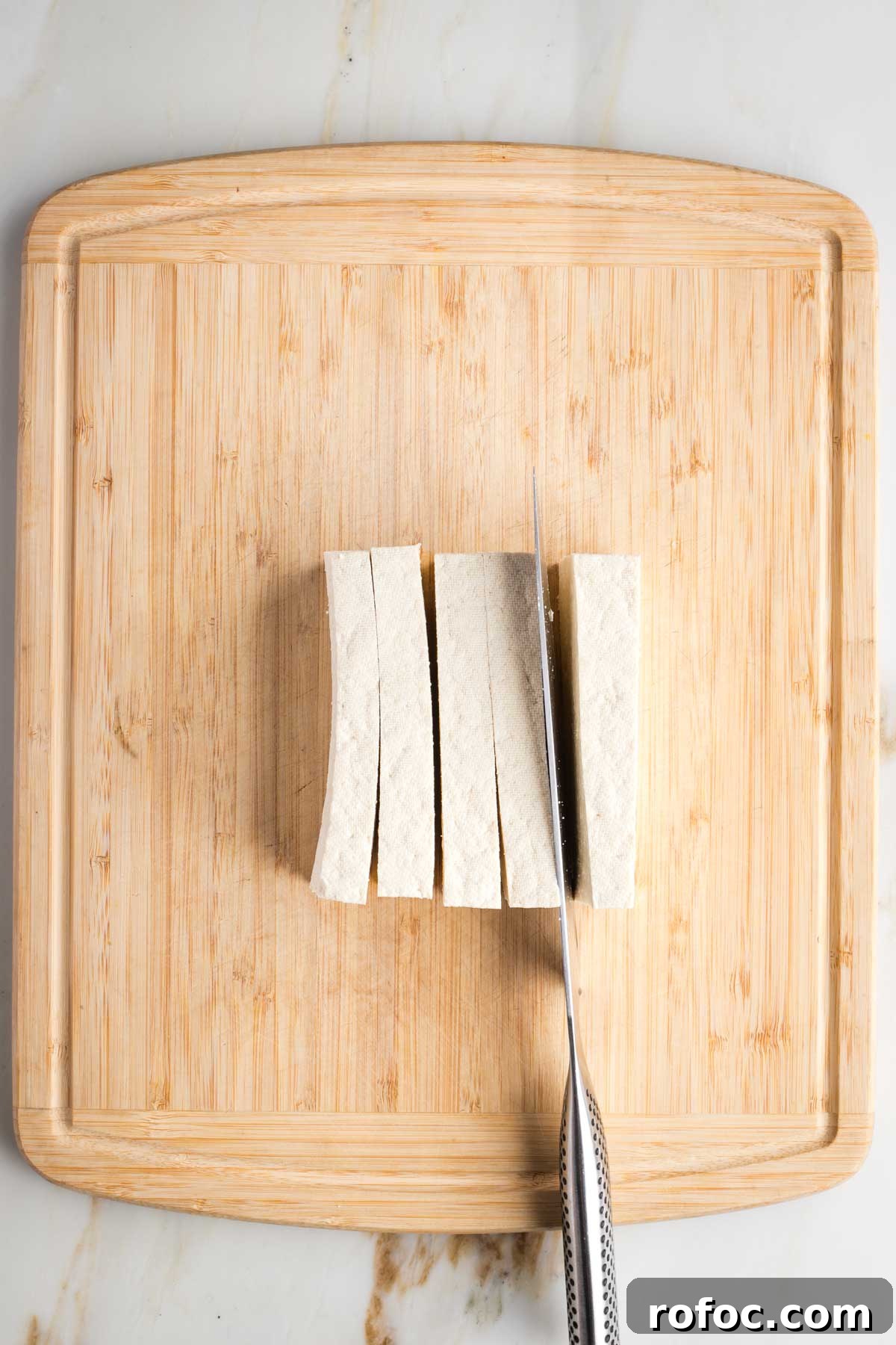 Crispy Orange Tofu — Restaurant-Style Takeout at Home 5 Cutting strips of tofu from a block on a cutting board.