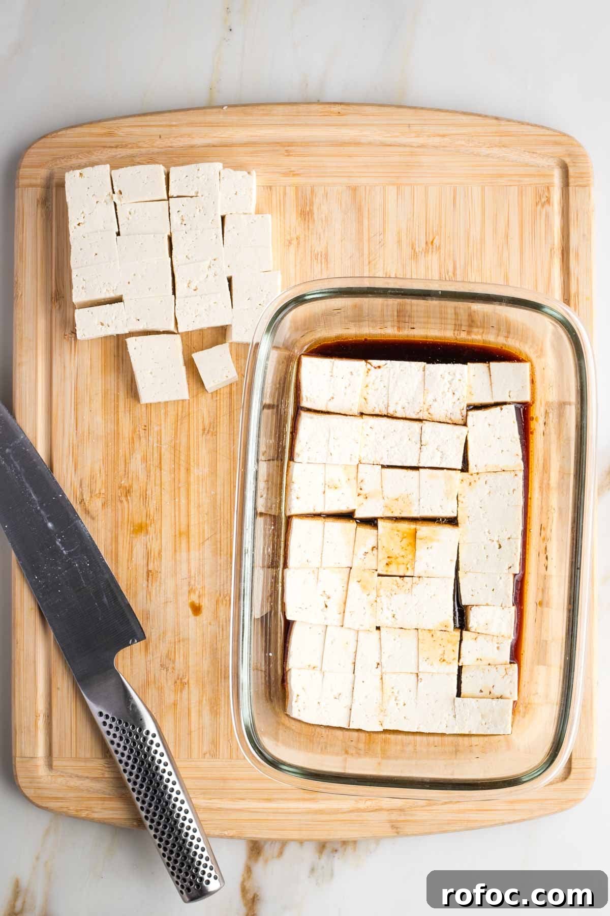 Crispy Orange Tofu — Restaurant-Style Takeout at Home 6 Cubes of tofu cut and then placed into a glass dish with soy sauce marinade.