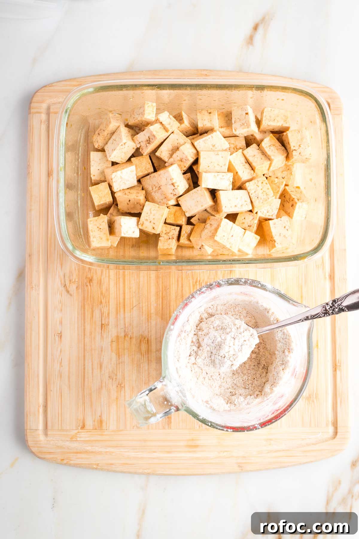 Crispy Orange Tofu — Restaurant-Style Takeout at Home 7 Cup of spiced arrowroot powder next to a dish of tofu cubes.