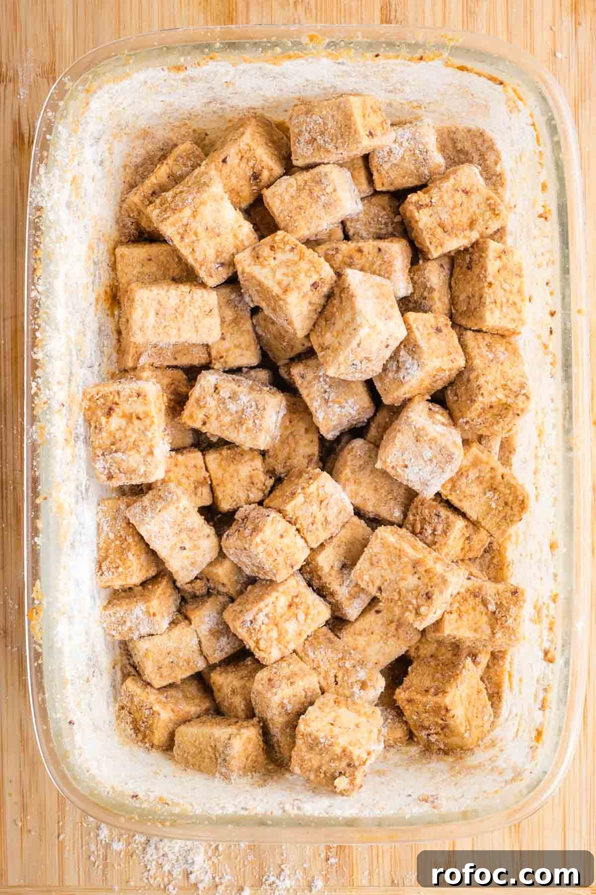Crispy Orange Tofu — Restaurant-Style Takeout at Home 8 Coated tofu cubes in a glass dish.