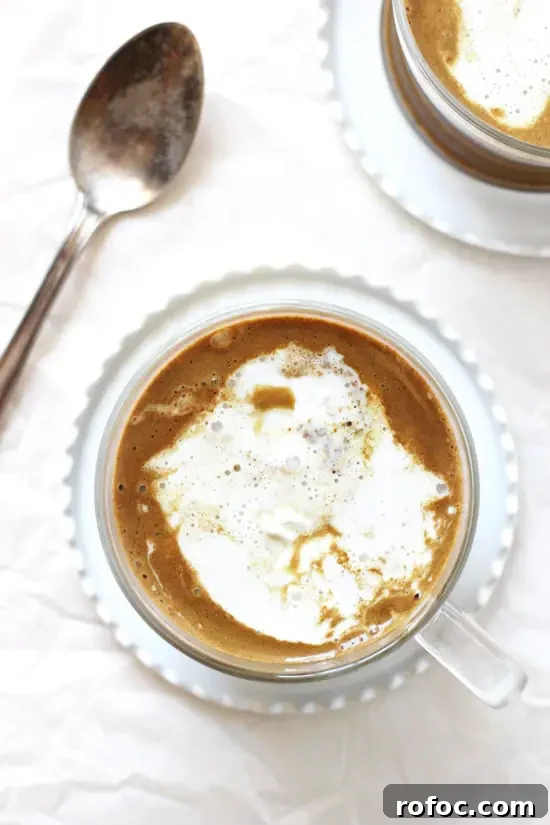 Cozy and calming, this chocolate golden milk is a delightful bedtime treat! Made in 10 minutes or less! With warm almond milk, spices and cocoa powder! Vegan & dairy free! An overhead view of two mugs of Chocolate Golden Milk topped with whipped coconut cream.