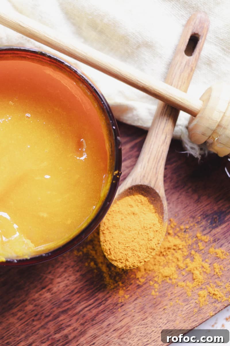 DIY Gel Sea Moss Face Mask Recipe for Glowing Skin 11 Freshly made sea moss face mask on a wooden board with a spoon full of turmeric powder next to it.