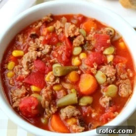 Hearty Crock Pot Beef and Vegetable Soup Recipe 6 A crock pot full of hearty vegetable beef soup, brimming with corn, carrots, green beans, and tomatoes.