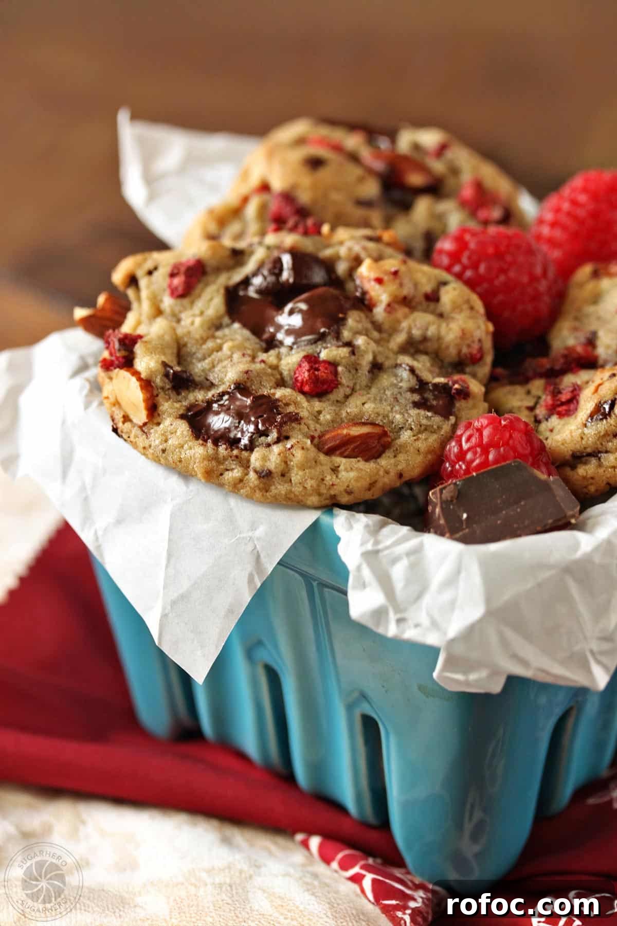 Raspberry Almond Chocolate Chunk Cookies - soft almond-flavored cookies with tangy dried raspberries and chocolate chunks. Raspberry Almond Chocolate Chunk Cookies - a straight shot of the cookies displayed in a blue basket. | From SugarHero.com