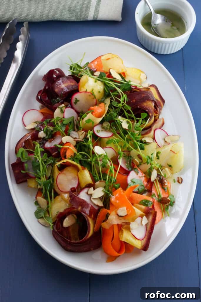 Spring Carrot and Pea Shoot Salad with Lemon Vinaigrette 2 An Overhead shot of a white platter with multicolored carrot ribbons, green pea shoots, thinly sliced radishes, sliced almonds drizzled with a lemon and herb dressing.